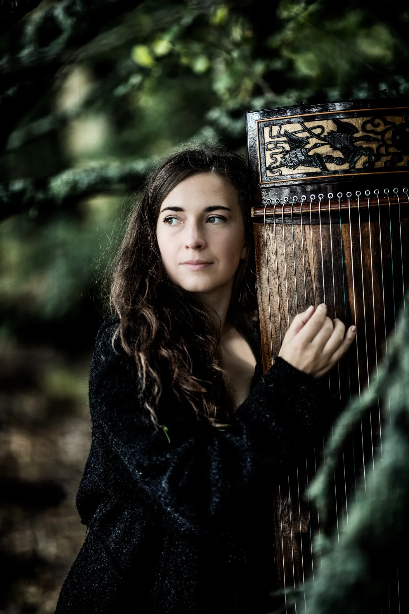 Barbora Xu holding her guzheng in the forest